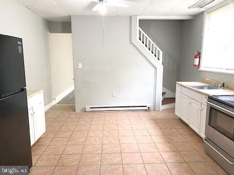 1364 Park Blvd, Camden, NJ 08103 - kitchen with stainless steel range with electric stovetop, freestanding refrigerator, a baseboard radiator, white cabinetry, and a sink