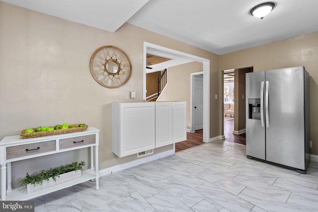 5421 Omaha Ave, Baltimore, MD 21206 - kitchen featuring stainless steel fridge, light marble finish floors, white cabinets, and baseboards