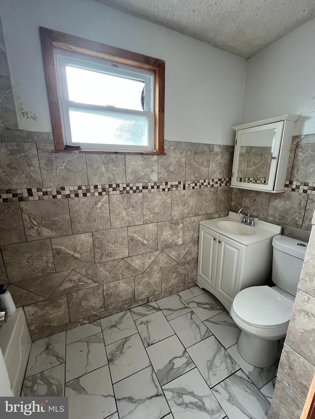 3639 N Darien St, Philadelphia, PA 19140 - bathroom featuring tile walls, toilet, a textured ceiling, vanity, and a wainscoted wall