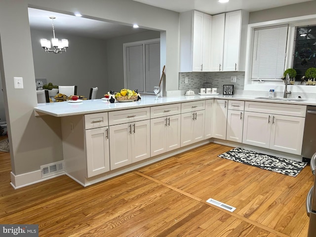 3701 Lochearn Dr, Gwynn Oak, MD 21207 - kitchen with a peninsula, light wood-style flooring, white cabinets, a sink, and light countertops