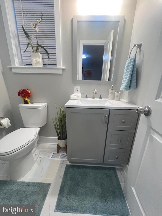 3701 Lochearn Dr, Gwynn Oak, MD 21207 - bathroom with marble look tiles, toilet, vanity, and baseboards