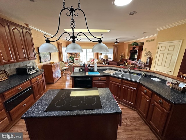 5054 Valley Stream Ln, Macungie, PA 18062 - kitchen with a center island, black electric stovetop, a sink, light wood finished floors, and crown molding