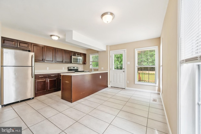 216 Parker Ave, Philadelphia, PA 19128 - kitchen with appliances with stainless steel finishes, light countertops, a peninsula, dark brown cabinets, and light tile patterned floors