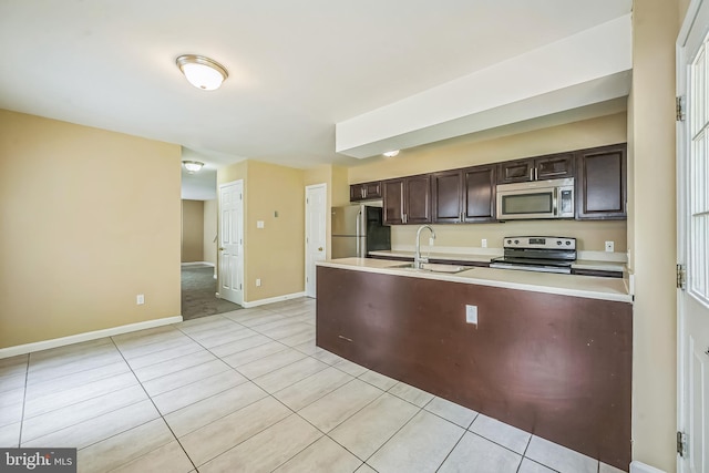 216 Parker Ave, Philadelphia, PA 19128 - kitchen featuring stainless steel appliances, dark brown cabinetry, light countertops, a sink, and light tile patterned floors
