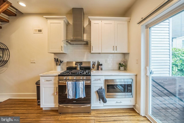 1809 Wilder St, Philadelphia, PA 19146 - kitchen with stainless steel appliances, wall chimney exhaust hood, light wood-style flooring, light countertops, and backsplash