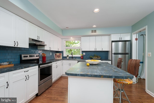 9 Laurel Wood, Lawrenceville, NJ 08648 - kitchen with appliances with stainless steel finishes, under cabinet range hood, a sink, a breakfast bar area, and decorative backsplash