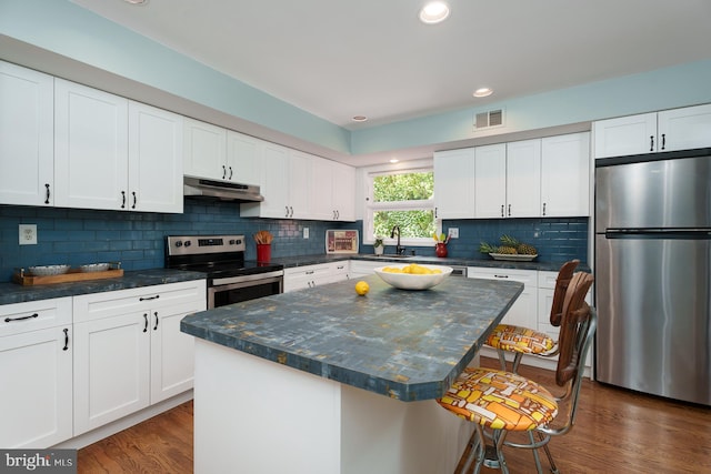 9 Laurel Wood, Lawrenceville, NJ 08648 - kitchen featuring appliances with stainless steel finishes, under cabinet range hood, a kitchen bar, dark countertops, and recessed lighting