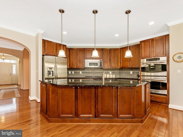 2507 Island Grove Blvd, Frederick, MD 21701 - kitchen with stainless steel appliances, arched walkways, light wood-style flooring, decorative backsplash, and ornamental molding