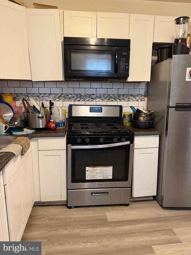 3141 W Norris St, Philadelphia, PA 19121 - kitchen with stainless steel appliances, light wood-style flooring, dark countertops, and white cabinets