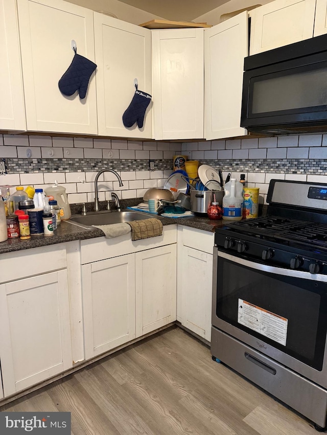 3141 W Norris St, Philadelphia, PA 19121 - kitchen with gas range, black microwave, a sink, white cabinets, and light wood finished floors