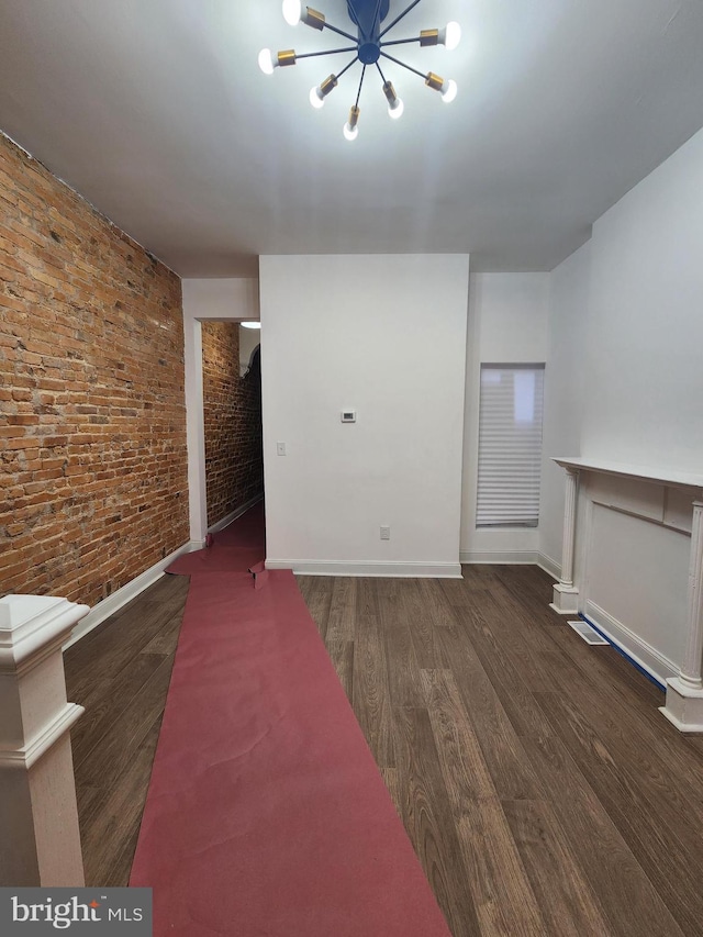 2218 Ruskin Ave, Baltimore, MD 21217 - unfurnished living room featuring wood finished floors, brick wall, a chandelier, and baseboards