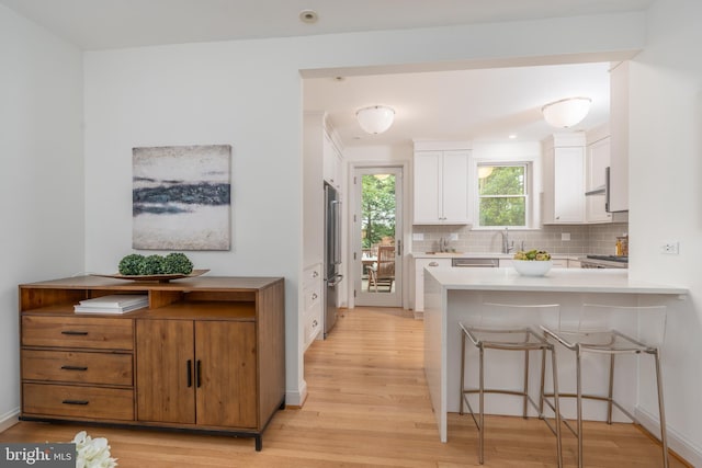 3709 Jocelyn St NW, Washington, DC 20015 - kitchen with light wood-style flooring, white cabinets, tasteful backsplash, and a peninsula