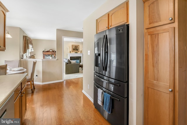 1219 N Valley Ave, Vineland, NJ 08360 - kitchen featuring stainless steel fridge, light wood-style floors, baseboards, a glass covered fireplace, and light countertops