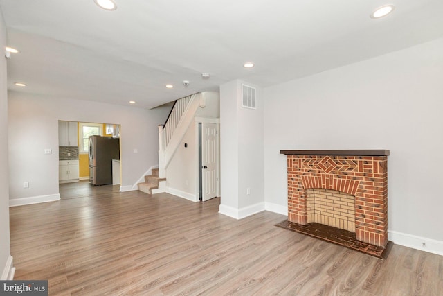 3327 Richmond Ave, Baltimore, MD 21213 - unfurnished living room featuring wood finished floors, stairway, recessed lighting, a brick fireplace, and baseboards