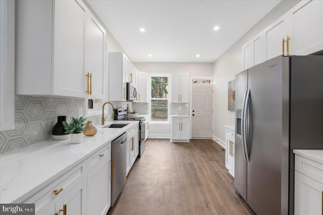 724 E 21st St, Baltimore, MD 21218 - kitchen with appliances with stainless steel finishes, a sink, white cabinetry, wood finished floors, and tasteful backsplash