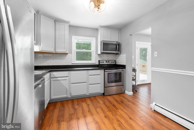 1704 Horner Rd, Woodbridge, VA 22191 - kitchen featuring stainless steel appliances, baseboard heating, decorative backsplash, dark countertops, and wood finished floors