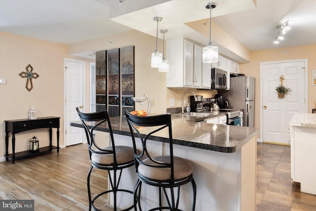 649 Brandon Rd, Eagleville, PA 19403 - kitchen featuring appliances with stainless steel finishes, a breakfast bar, a sink, white cabinetry, and a peninsula