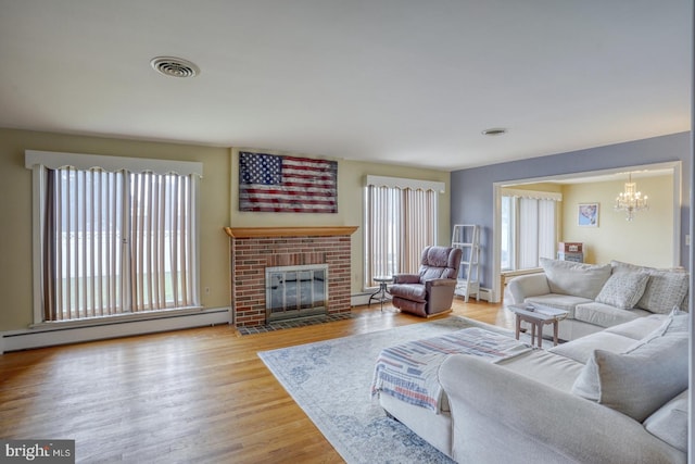 333 S School Ln, Smyrna, DE 19977 - living area featuring a baseboard heating unit, a chandelier, wood finished floors, and a fireplace