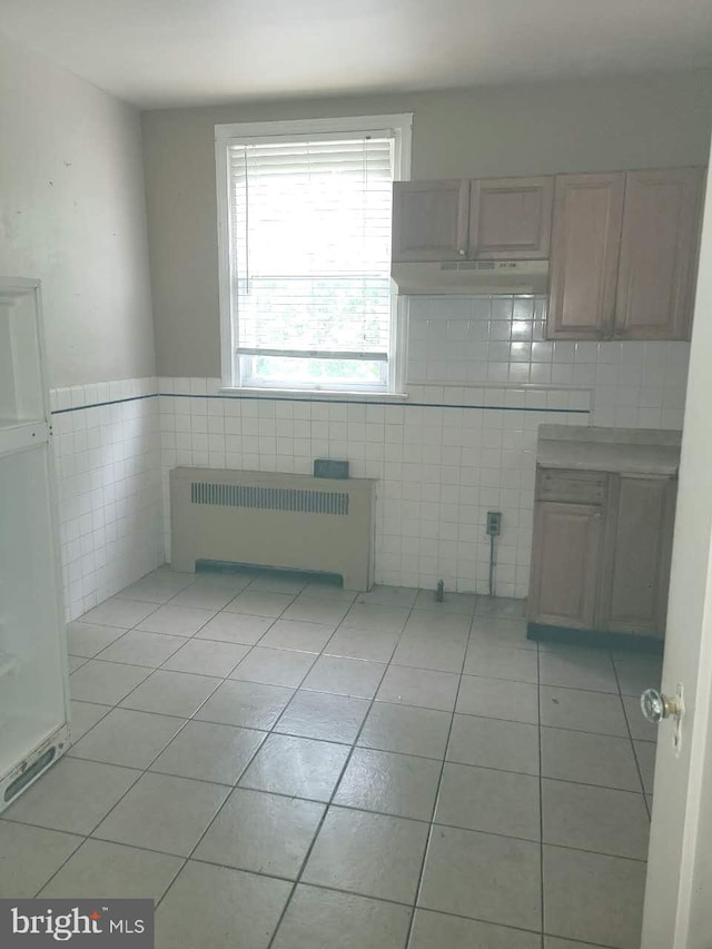 5137 D St, Philadelphia, PA 19120 - unfurnished dining area featuring radiator heating unit, tile walls, light tile patterned floors, and a wainscoted wall