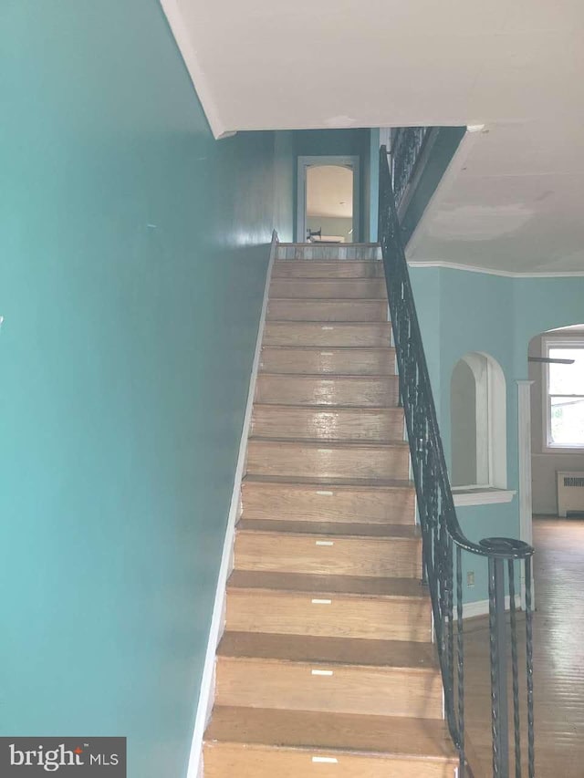5137 D St, Philadelphia, PA 19120 - staircase featuring wood finished floors, radiator heating unit, arched walkways, and baseboards