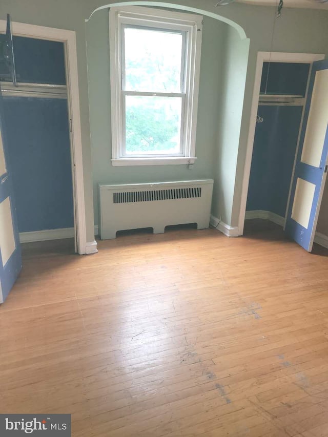 5137 D St, Philadelphia, PA 19120 - unfurnished bedroom featuring radiator heating unit, hardwood / wood-style floors, baseboards, and arched walkways