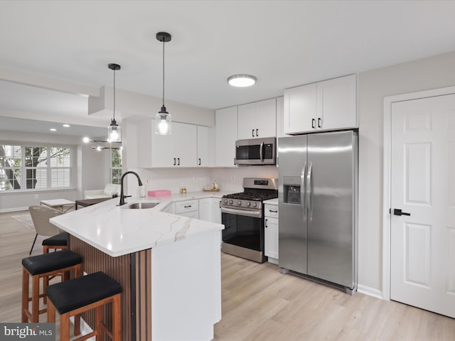 14282 Newbern Loop, Gainesville, VA 20155 - kitchen featuring appliances with stainless steel finishes, a sink, a peninsula, light wood-type flooring, and a kitchen breakfast bar