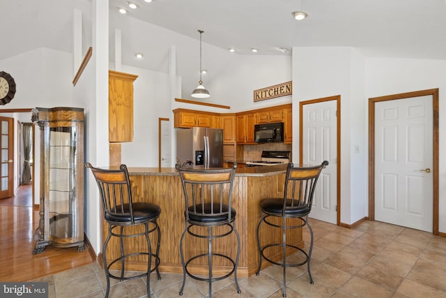 25 Warm Breeze Ct, Hanover, PA 17331 - kitchen featuring stainless steel fridge with ice dispenser, black microwave, gas range, a peninsula, and brown cabinetry