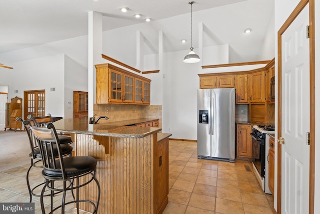 25 Warm Breeze Ct, Hanover, PA 17331 - kitchen featuring stainless steel fridge with ice dispenser, range with gas cooktop, a peninsula, brown cabinets, and high vaulted ceiling
