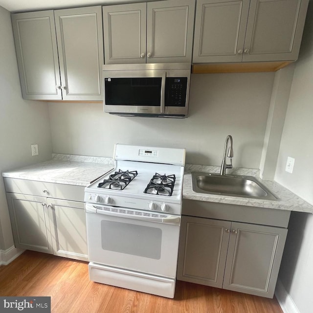 8528 Chestnut Oak, Baltimore, MD 21234 - kitchen featuring stainless steel microwave, white gas range oven, gray cabinets, a sink, and light wood-style floors
