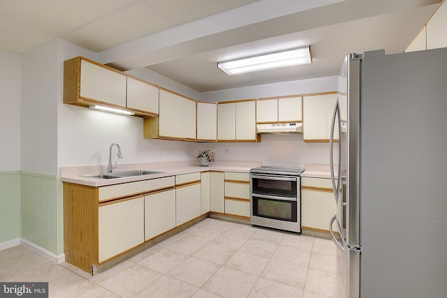 2119 Saint Heather Ln, Gambrills, MD 21054 - kitchen with appliances with stainless steel finishes, a sink, under cabinet range hood, light countertops, and a wainscoted wall