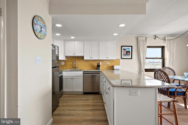 3801 Atlantic Ave Unit 517, Ocean City, MD 21842 - kitchen with stainless steel dishwasher, a peninsula, wood finished floors, white cabinetry, and recessed lighting