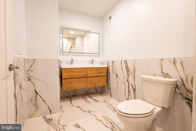 2039 S Cleveland St, Philadelphia, PA 19145 - bathroom featuring double vanity, toilet, marble finish flooring, wainscoting, and tile walls