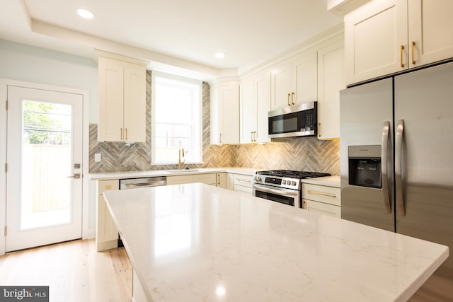 2039 S Cleveland St, Philadelphia, PA 19145 - kitchen featuring stainless steel appliances, a sink, light stone counters, a kitchen island, and backsplash