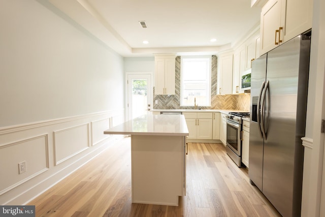 2039 S Cleveland St, Philadelphia, PA 19145 - kitchen featuring stainless steel appliances, a kitchen island, tasteful backsplash, light countertops, and light wood-style floors