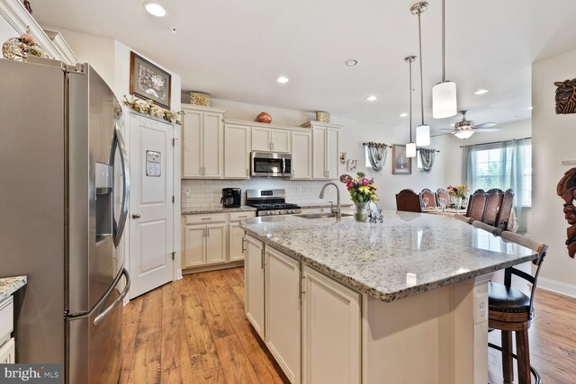 5544 Old Colony Ct, White Plains, MD 20695 - kitchen with stainless steel appliances, a sink, light wood-style floors, a ceiling fan, and tasteful backsplash