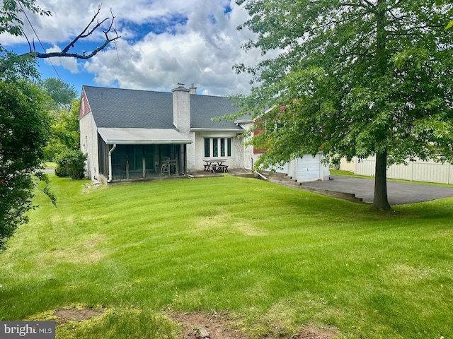 713 Worthington Dr, Warminster, PA 18974 - rear view of house with a sunroom, a chimney, a shingled roof, a patio area, and asphalt driveway