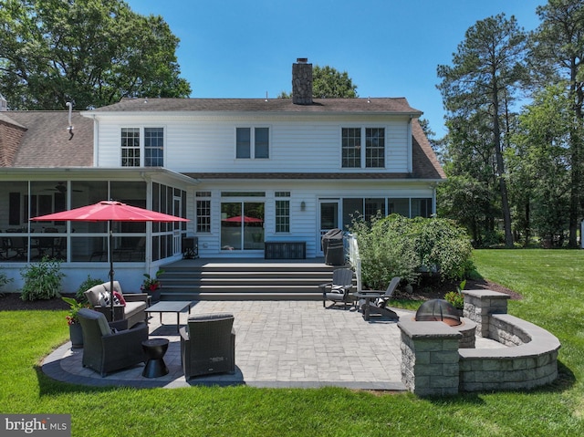 205 Mallard Dr, Stevensville, MD 21666 - back of property with a sunroom, a patio, a chimney, a lawn, and an outdoor fire pit