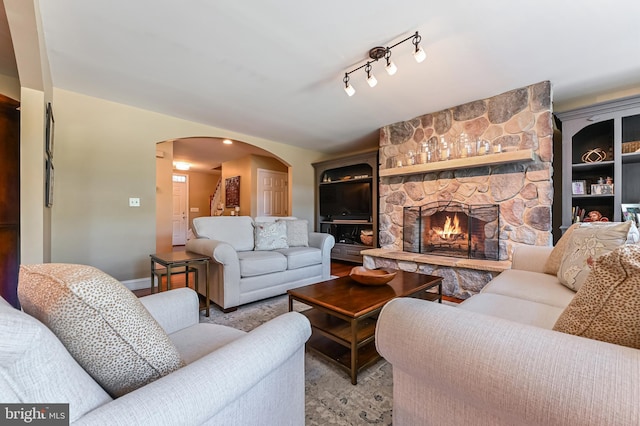 205 Mallard Dr, Stevensville, MD 21666 - living room featuring arched walkways, a stone fireplace, and baseboards