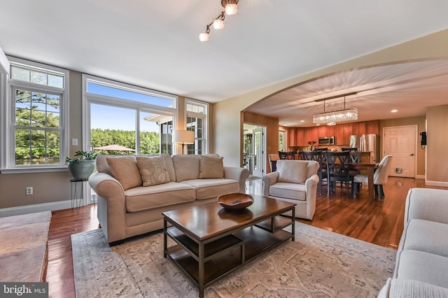 205 Mallard Dr, Stevensville, MD 21666 - living room featuring arched walkways, wood finished floors, baseboards, and a chandelier