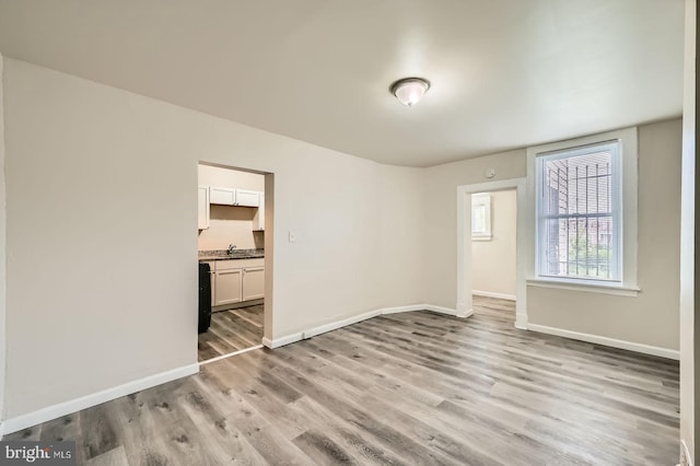 118 N Hilton St, Baltimore, MD 21229 - spare room featuring light wood-style flooring, baseboards, and a sink