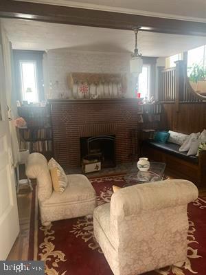 19 S Elberon Ave, Atlantic City, NJ 08401 - living room with a brick fireplace, plenty of natural light, wood finished floors, and crown molding