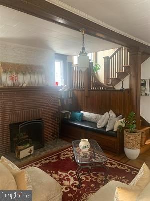 19 S Elberon Ave, Atlantic City, NJ 08401 - living room featuring crown molding, wood finished floors, a brick fireplace, and stairs