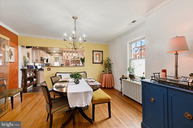 4224 Evans Chapel Rd, Baltimore, MD 21211 - dining room featuring a chandelier, radiator heating unit, ornamental molding, light wood finished floors, and baseboards