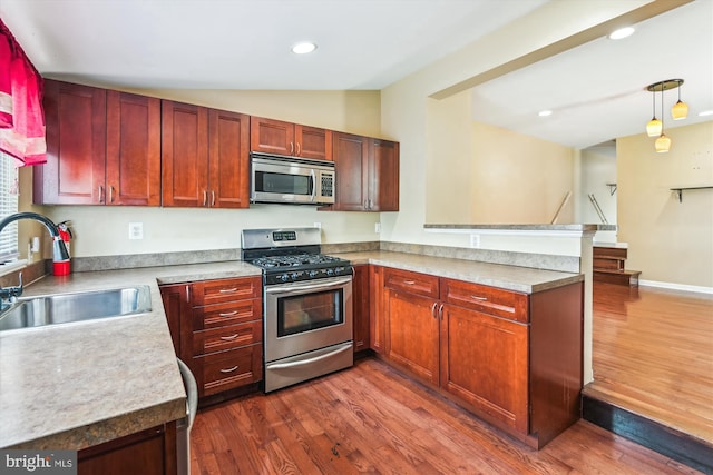 3603 6th St, Baltimore, MD 21225 - kitchen with stainless steel appliances, a sink, vaulted ceiling, a peninsula, and dark wood-style flooring