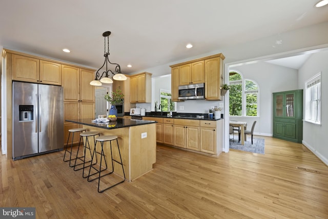 3403 Niagara Rd, Annapolis, MD 21403 - kitchen with appliances with stainless steel finishes, light wood-type flooring, a breakfast bar area, a kitchen island, and dark countertops