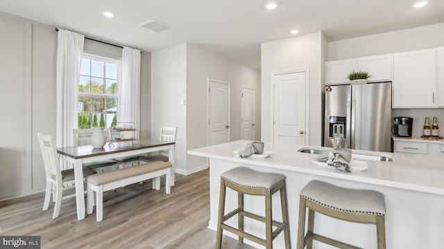 210 Bentz Ave, Villas, NJ 08251 - kitchen featuring stainless steel fridge, white cabinets, light countertops, light wood-style flooring, and a breakfast bar area