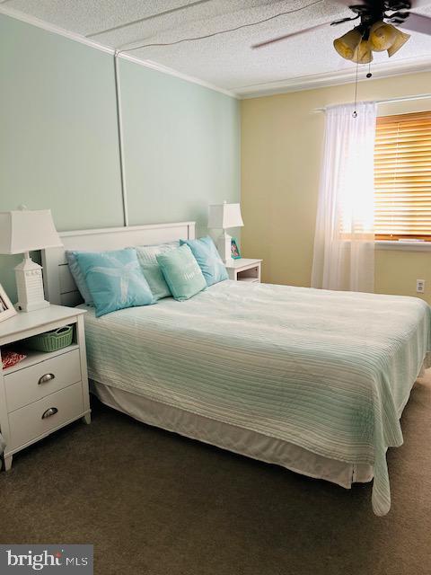 13 60th St Unit 201, Ocean City, MD 21842 - bedroom with ornamental molding, a textured ceiling, dark colored carpet, and ceiling fan
