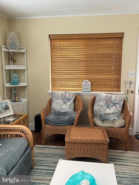 13 60th St Unit 201, Ocean City, MD 21842 - sitting room featuring wood finished floors, ornamental molding, a textured ceiling, and baseboards
