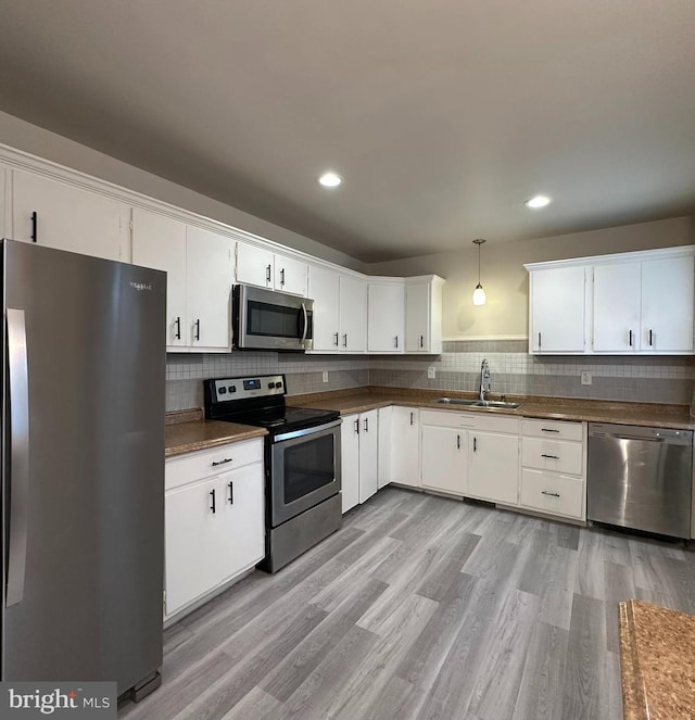 33 New Dorwart St, Lancaster, PA 17603 - kitchen featuring appliances with stainless steel finishes, a sink, light wood-type flooring, tasteful backsplash, and white cabinetry