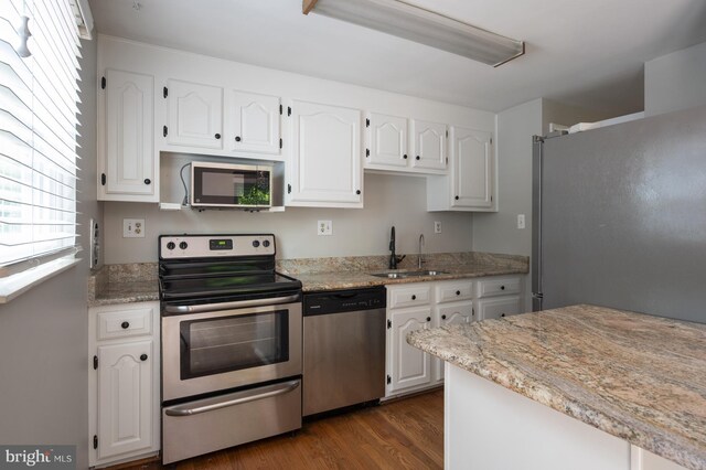 1100 Clarke St, Herndon, VA 20170 - kitchen featuring stainless steel appliances, a sink, white cabinets, dark wood finished floors, and light stone counters